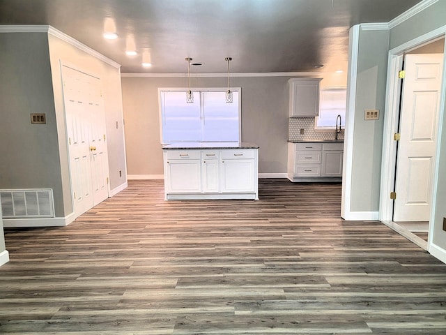 kitchen featuring decorative light fixtures, sink, ornamental molding, and tasteful backsplash