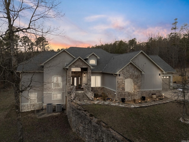 view of front facade with central AC unit, a garage, and a lawn