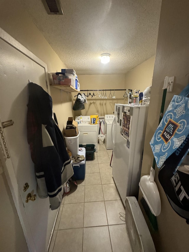 laundry room featuring a textured ceiling, light tile patterned floors, and independent washer and dryer