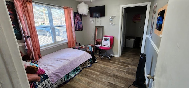 bedroom with multiple windows and dark hardwood / wood-style flooring