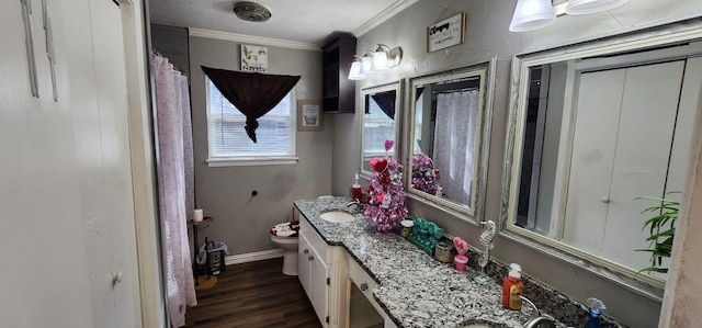 bathroom featuring toilet, vanity, hardwood / wood-style flooring, a textured ceiling, and ornamental molding