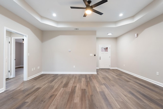 spare room with ceiling fan, dark hardwood / wood-style floors, and a tray ceiling