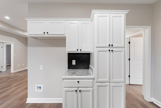 kitchen featuring light hardwood / wood-style floors, backsplash, and white cabinets