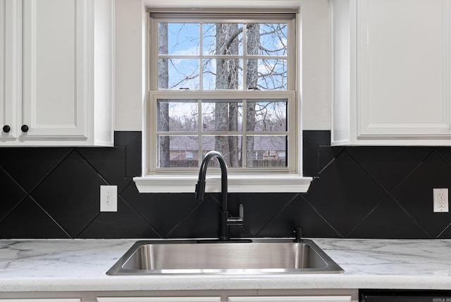 kitchen with light stone counters, sink, and white cabinetry