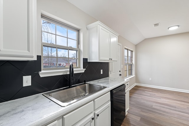 kitchen featuring black dishwasher, light wood-type flooring, vaulted ceiling, white cabinets, and sink