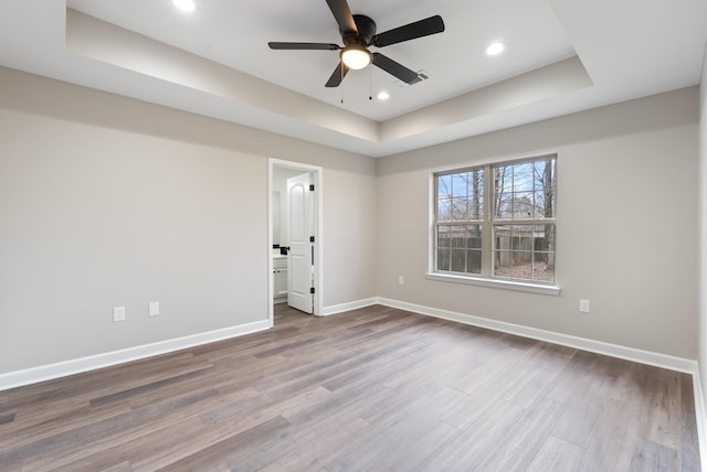 spare room featuring ceiling fan, a tray ceiling, and hardwood / wood-style floors