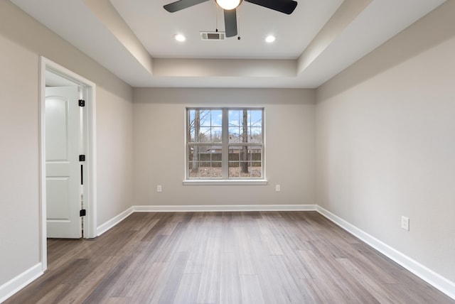 spare room featuring hardwood / wood-style flooring, ceiling fan, and a raised ceiling