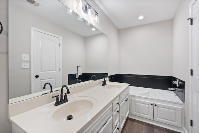 bathroom with a bath, hardwood / wood-style floors, and vanity