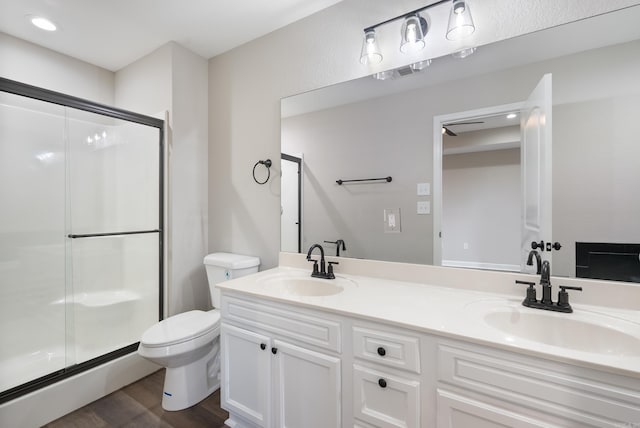 bathroom featuring toilet, hardwood / wood-style floors, a shower with door, and vanity