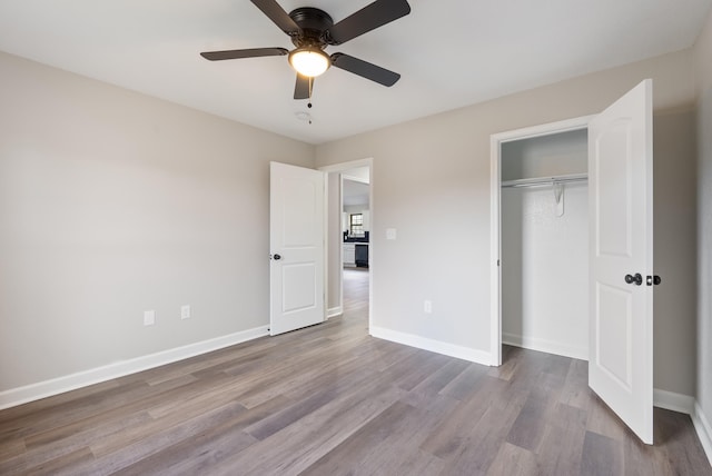 unfurnished bedroom featuring ceiling fan, a closet, and light wood-type flooring