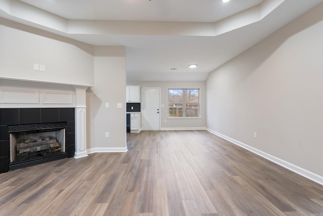 unfurnished living room with light hardwood / wood-style floors and a tiled fireplace