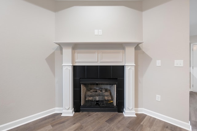 details featuring a tiled fireplace and hardwood / wood-style floors