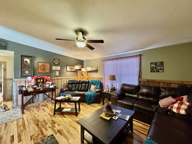 living room with ceiling fan, a textured ceiling, hardwood / wood-style flooring, and lofted ceiling