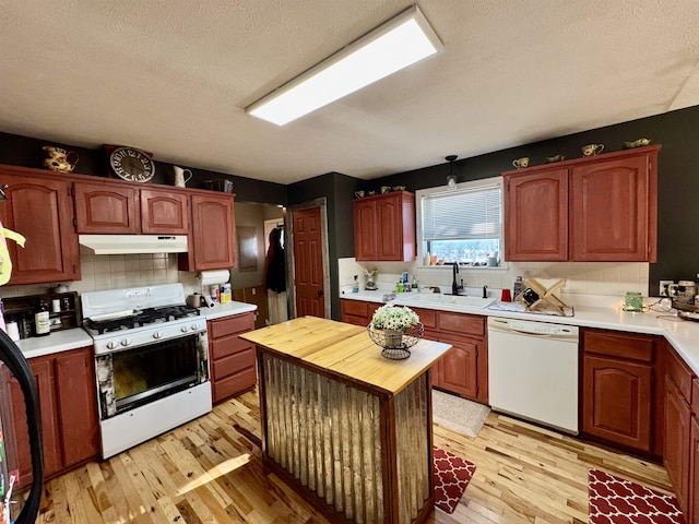 kitchen with white appliances, a textured ceiling, decorative backsplash, sink, and light wood-type flooring