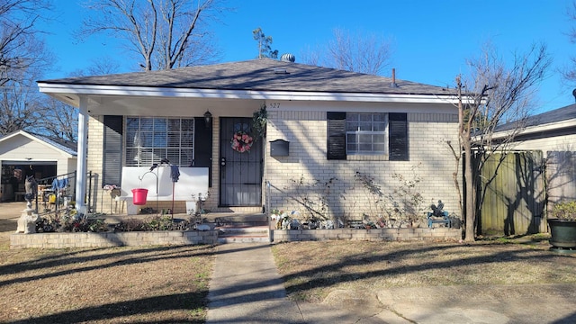 bungalow-style home featuring a garage, a front yard, an outdoor structure, and covered porch