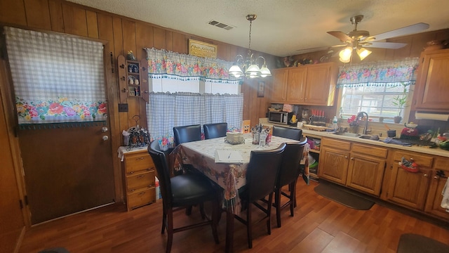 dining room featuring a textured ceiling, ceiling fan with notable chandelier, dark hardwood / wood-style floors, and sink