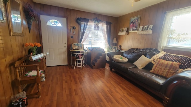 living room with ceiling fan, dark hardwood / wood-style floors, and wooden walls