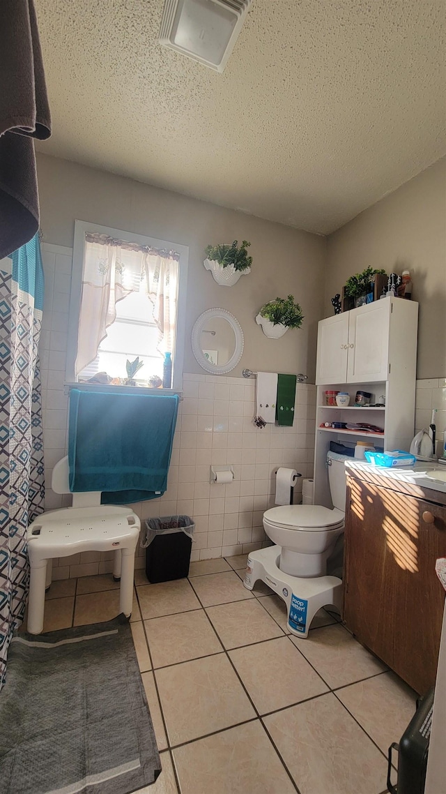 bathroom with tile patterned flooring, tile walls, toilet, and a textured ceiling