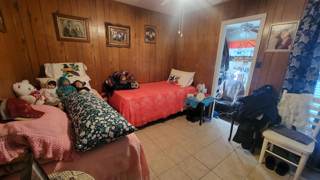 bedroom with ceiling fan, light tile patterned floors, and wooden walls