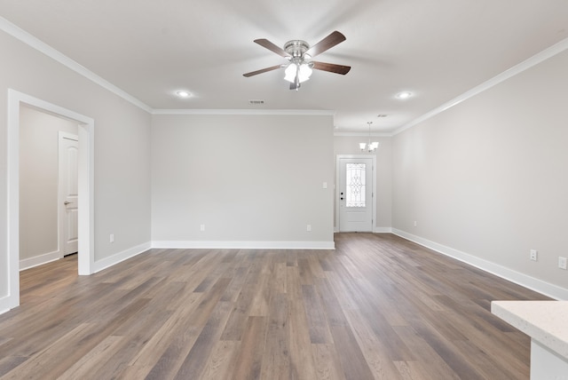 empty room with ceiling fan with notable chandelier, dark hardwood / wood-style flooring, and ornamental molding