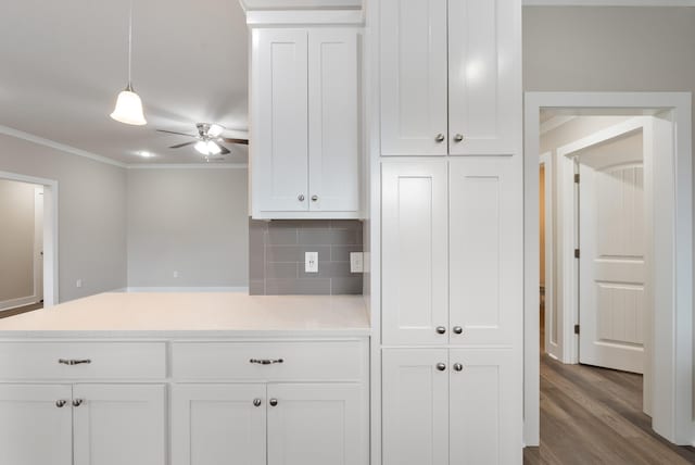 kitchen with hanging light fixtures, white cabinets, and crown molding