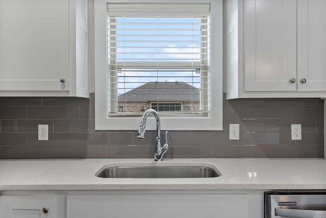 kitchen featuring white cabinets, backsplash, sink, and light stone counters