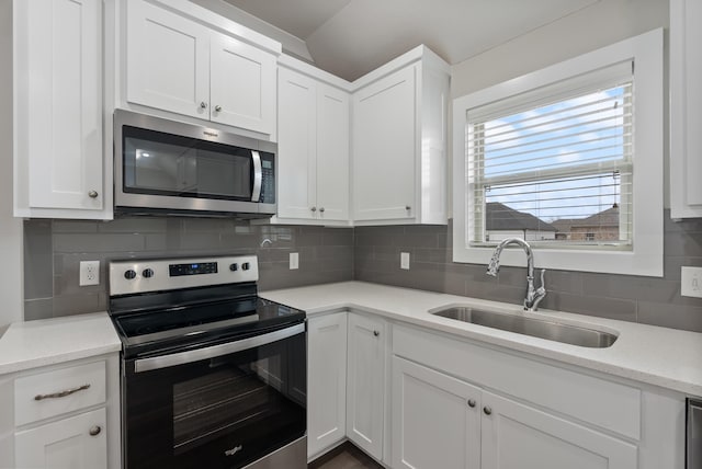 kitchen with stainless steel appliances, decorative backsplash, white cabinetry, and sink