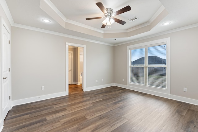 spare room with ceiling fan, ornamental molding, dark hardwood / wood-style flooring, and a tray ceiling