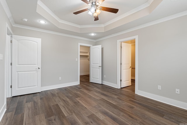 unfurnished bedroom featuring ceiling fan, dark hardwood / wood-style floors, a raised ceiling, and ornamental molding