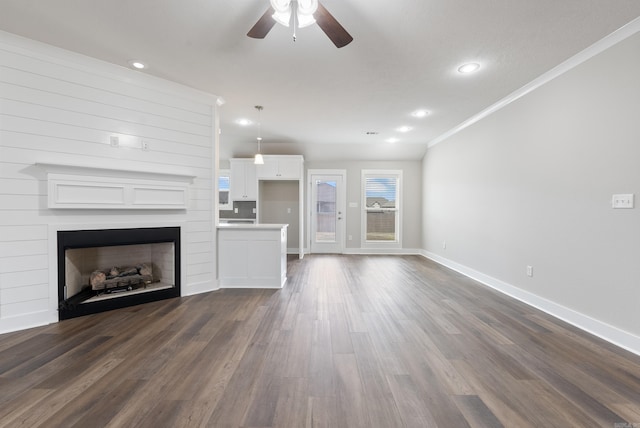 unfurnished living room with ceiling fan, dark hardwood / wood-style flooring, and ornamental molding