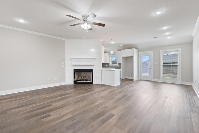 unfurnished living room with ceiling fan, a fireplace, ornamental molding, and hardwood / wood-style floors