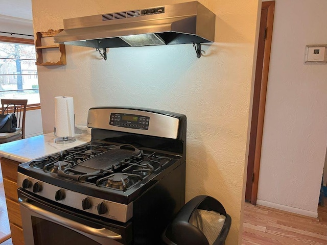 kitchen with extractor fan, light wood-type flooring, and stainless steel gas range