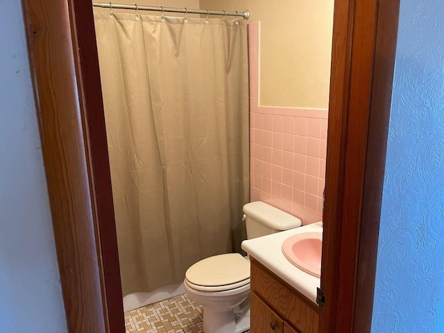 bathroom featuring tile walls, toilet, and vanity