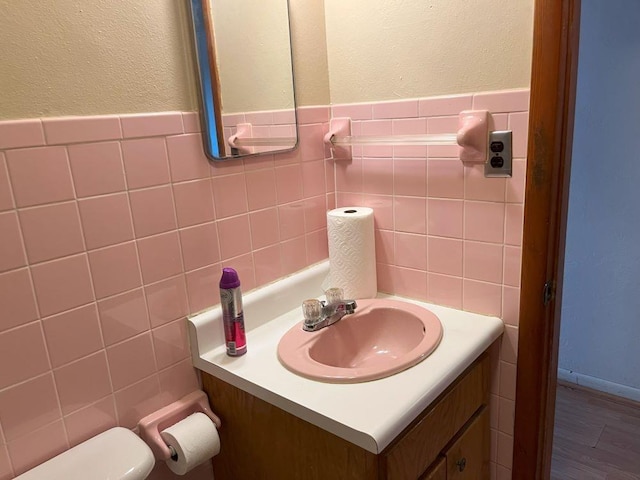 bathroom with toilet, vanity, and tile walls