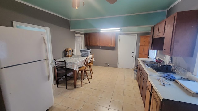 kitchen with white refrigerator, ornamental molding, and light tile patterned flooring