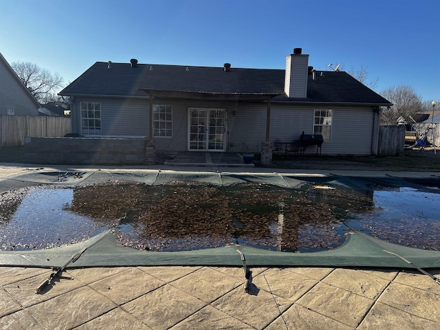 rear view of house with a covered pool and a patio