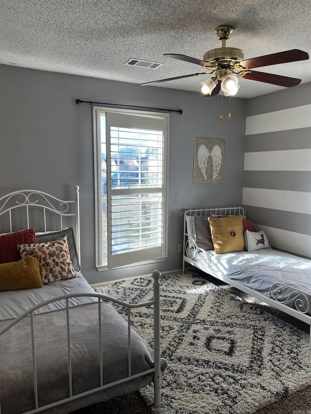 bedroom with ceiling fan and a textured ceiling