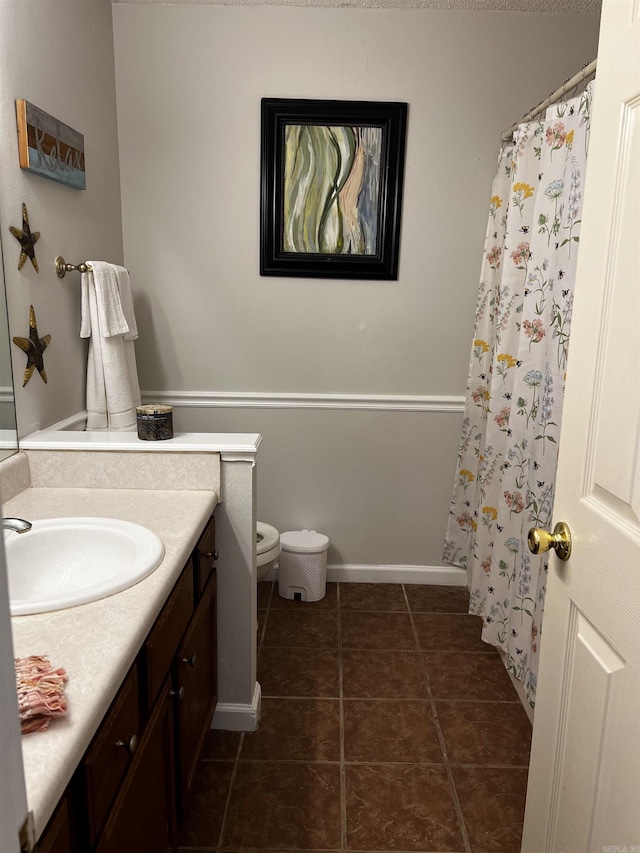 bathroom with toilet, vanity, and tile patterned flooring