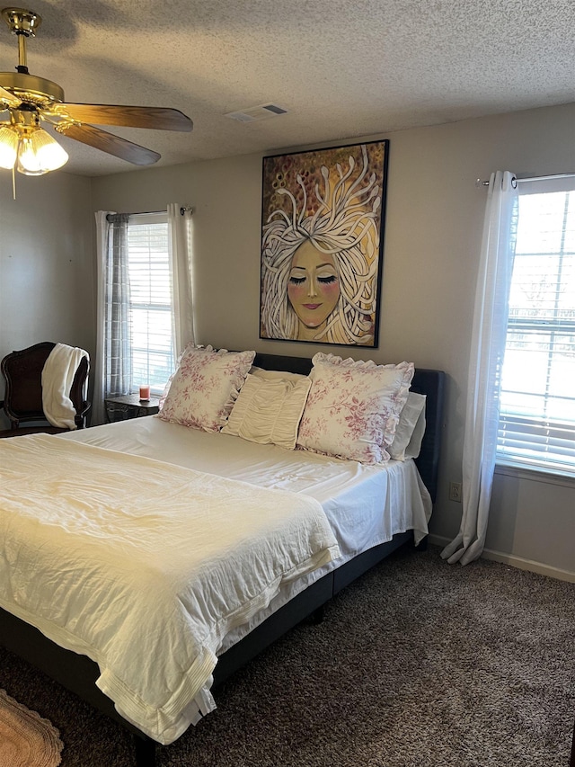 bedroom featuring a textured ceiling, ceiling fan, carpet, and multiple windows