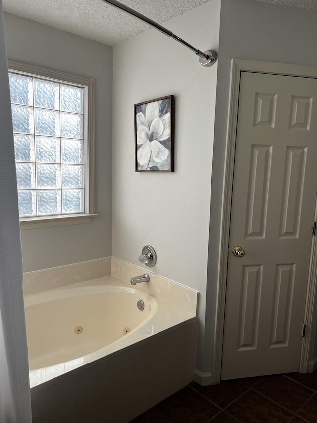 bathroom featuring a textured ceiling, tile patterned flooring, and a tub