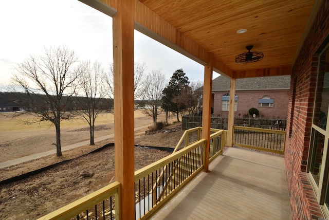 deck with a rural view and covered porch