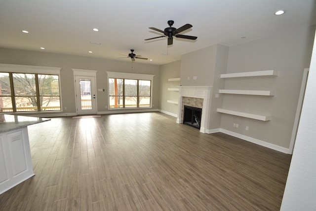 unfurnished living room featuring ceiling fan, dark hardwood / wood-style floors, built in features, and a tiled fireplace