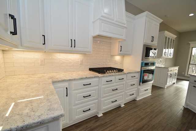 kitchen featuring dark wood-type flooring, white cabinets, appliances with stainless steel finishes, and light stone countertops