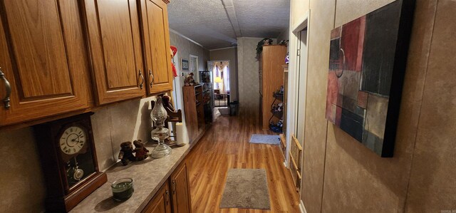 corridor featuring crown molding, a textured ceiling, and light hardwood / wood-style floors