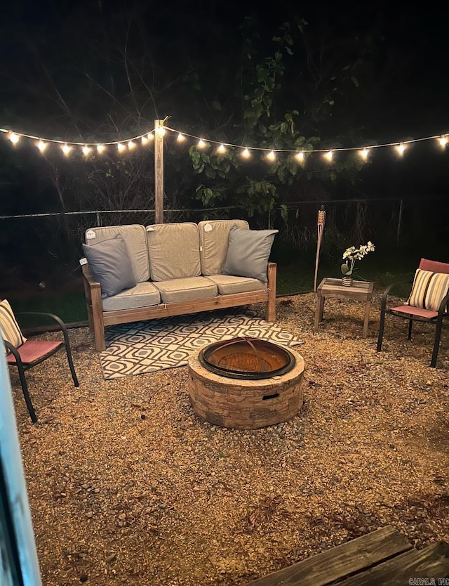 patio at night with an outdoor living space with a fire pit