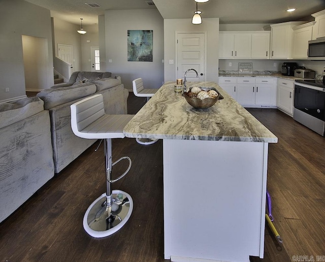 kitchen with a breakfast bar area, white cabinets, an island with sink, and stainless steel appliances