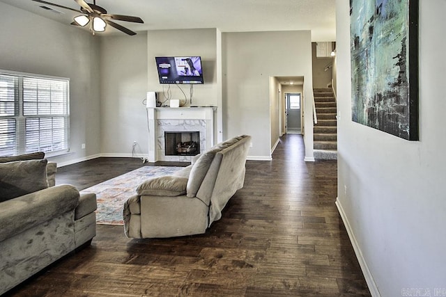 living room with a premium fireplace, dark hardwood / wood-style floors, and ceiling fan