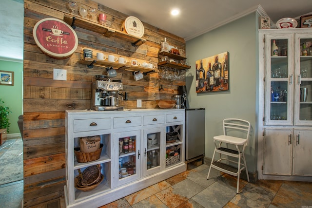 bar with wooden walls, white cabinetry, and ornamental molding