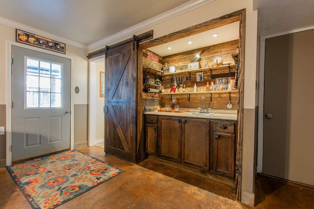 bar featuring sink, dark brown cabinetry, a barn door, and crown molding