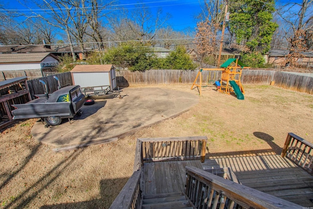 view of yard with a deck, a patio area, a playground, and a storage unit